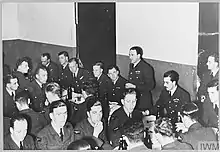 black and white photography of a man at a dinner table giving a speech to a room full of seated men