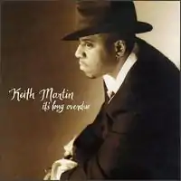 A sepia-tone image of a man wearing a suit and hat. Both the artist's name and album title appear in the center-left, written cursively in white.