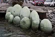 A large sculpture of spiky green shellfish sitting in the water, on the Wellington Waterfront.