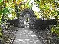 Temple enclosure wall and gate constructed using rubble stone masonry with native teak trees