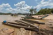 Beach of Don Khon, a sunny day with children running on the river bank, where several pirogues are attached.