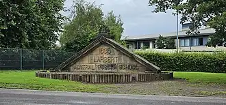 Photograph of stonework from the original school, mounted in the grounds of the new school. It is the lintel with the school name and the founding year of 1885.