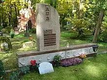 Gravestone with flowers at the base surrounded by grass