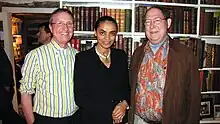 Waist high portrait of three middle aged people in the library of what could be a boat or other confined space.