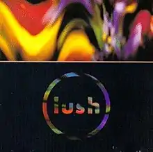 A psychedelic-style photograph featuring alternating shades of red, orange, purple and yellow. A white horizontal line in the centre cuts the image and the lower portion contains the words "Lush" and a circle in multicolor typeface against a black background.