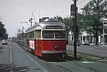 A streetcar at a small platform in the median of an urban street