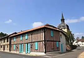 A timbered building and the church tower in Magescq