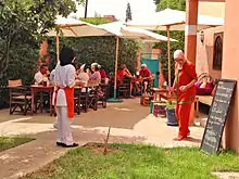 Trainees serving customers who are seated outside under umbrellas