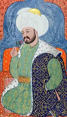 Persianate miniature showing a bearded man in rich robes and a large turban seated, and smelling a rose