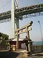 A torii standing with Kanmonkyo Bridge in background