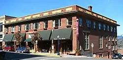 Photograph of a two-story brick building on a city street corner