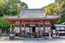 Wooden building with white walls, red beams and a hip-and-gable roof.