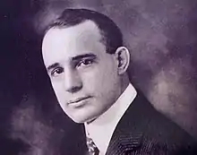 Photograph of head of young man clad in white shirt, jacket and tie.