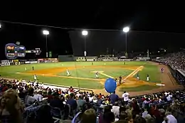 A green baseball field illuminated for a night game