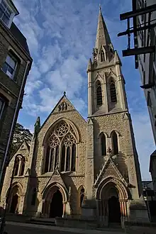 A large, grey stone church with two entrances either side and a steeple on the right.