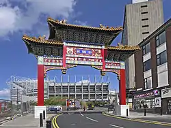 A wooden arch elaborately decorated in red and gold, over a street