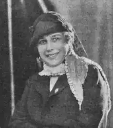 Grainy portrait photo of a smiling woman wearing a hat.