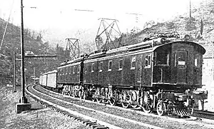 Electric locomotive with box cab pulls coal cars up grade