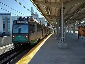 A light rail train at an elevated station in an urban area