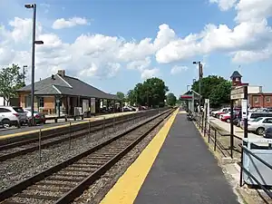 A suburban railway station with a yellow brick station building