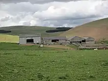 A picture of a farm in Old Hazeltonrig with Castle Hill pictured to the right.