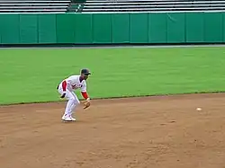 Player fielding a ground ball on a dirt infield