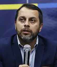 Image of Paul Granda holding a microphone during his intervention a minister of transportation during a transportation strike