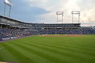 A green baseball field surrounded by navy blue seats with three light towers high above