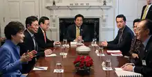 Two women and several men meeting around a table