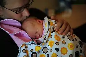 Father holding daughter in swaddling clothes