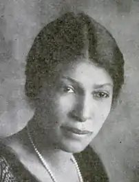 A young Black woman, dark hair dressed back with a center part, wearing pearls