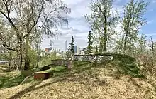 pehonan by Tiffany Shaw-Collinge in Indigenous Art Park, ᐄᓃᐤ (ÎNÎW) River Lot 11 on a spring day. Downtown Edmonton in the background.