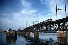 A stone bridge pier in a wide river, next to a steel truss bridge