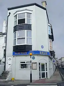 exterior of red bricked house, with blue plaque on front wall