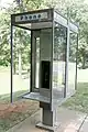 Partially enclosed pay phone in North Carolina, typical of many early replacements for telephone booths in the United States, continuing an enclosed space on three sides without the booth.