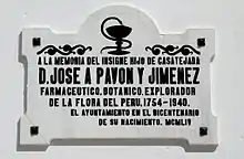 A white plaque reading: "A la memoria del insigne hijo de Casatejada, D. José A Pavón y Jimenez. Farmacéutico, botánico, explorador de la flora del Perú, 1754-1940 [sic]. El ayuntamiento en el bicentenario de su nacimiento. MCMLIV." In English: "In memory of the distinguished son of Castejada, D. José A Pavón y Jimenez. Pharmacist, botanist, explorer of flora in Peru, 1754-1940 [sic]. City Hall on the bicentennial of his birth. 1954." This incorrectly lists his death year as 1940 instead of 1840.