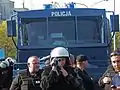 Polish Police's Anti-Riot Detachment, filming a gathering. The film can later be presented during a trial as evidence. A water cannon is seen in the background.