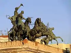 The bronze "Quadriga with Apollo and Euterpe" (the muse of lyric poetry) on the Teatro Politeama (1867–1874) in Palermo (Italy) by sculptor Mario Rutelli with riders on the sides  fashioned by Benedetto Civiletti.