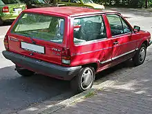  Rear-three-quarter view of a small three-door car with a flat roof, black-plastic bumpers, door mirrors, a sunroof, and hubcaps.