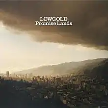 The album cover depicts a city surrounded by hills and a giant cloud that is on the right side of the image.