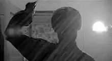 A silhouetted figure brandishes a knife towards the camera