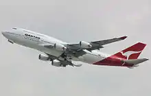 Side view of four-engine jet climbing in the sky.