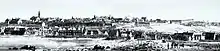 An illustration of Quebec City, with many buildings surrounding the waterfront to the bottom left. City walls may be observed in the background.