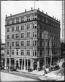 Black and white exterior photo of a six-storey brick building with in Victorian architecture, circa 1895