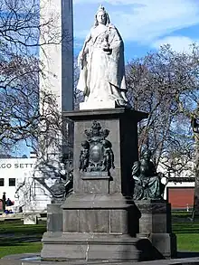 Large figure of a woman wearing a crown and robes, positioned on a tall plinth