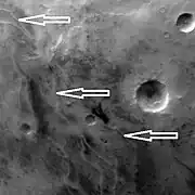 Ridges, believed to be eskers of the Dorsa Argentea Formation, as seen by Mars Global Surveyor wide angle MOC.  White arrows point to the ridges.