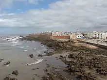 A seaside view of a large city enclosed by an orange barricade.