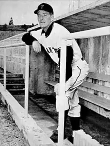 A man in a light baseball uniform and dark cap