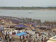 Large groups of people standing on the banks of a river in the afternoon