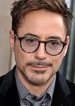 A headshot of Robert Downey Jr with glasses on smiling towards the camera